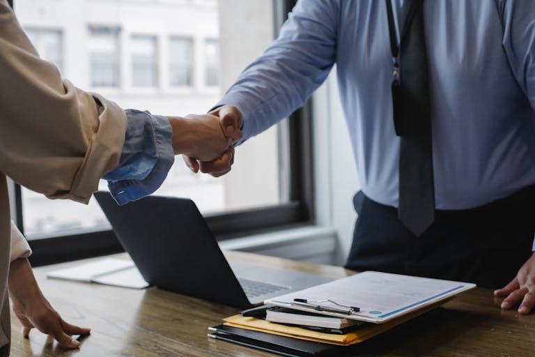 crop unrecognizable coworkers in formal wear standing at table with laptop and documents while greeting each other before meeting 5673488 768x512 Accueil